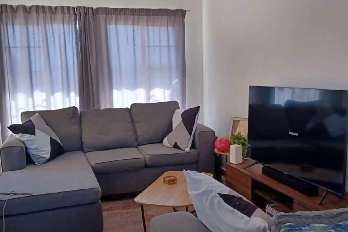 A comfortable living room featuring tiled flooring and a sliding glass door providing access to the exterior.