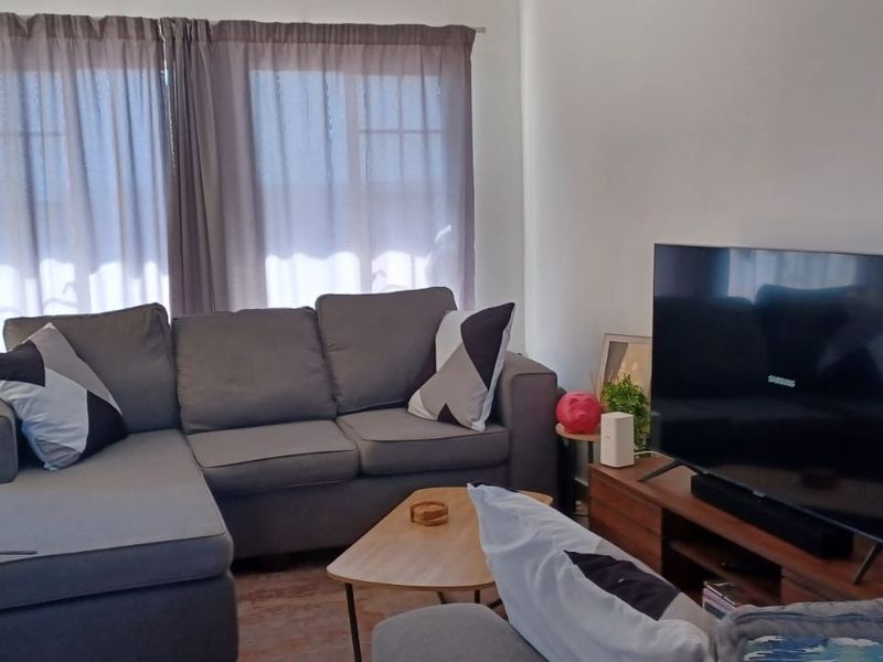 A comfortable living room featuring tiled flooring and a sliding glass door providing access to the exterior.