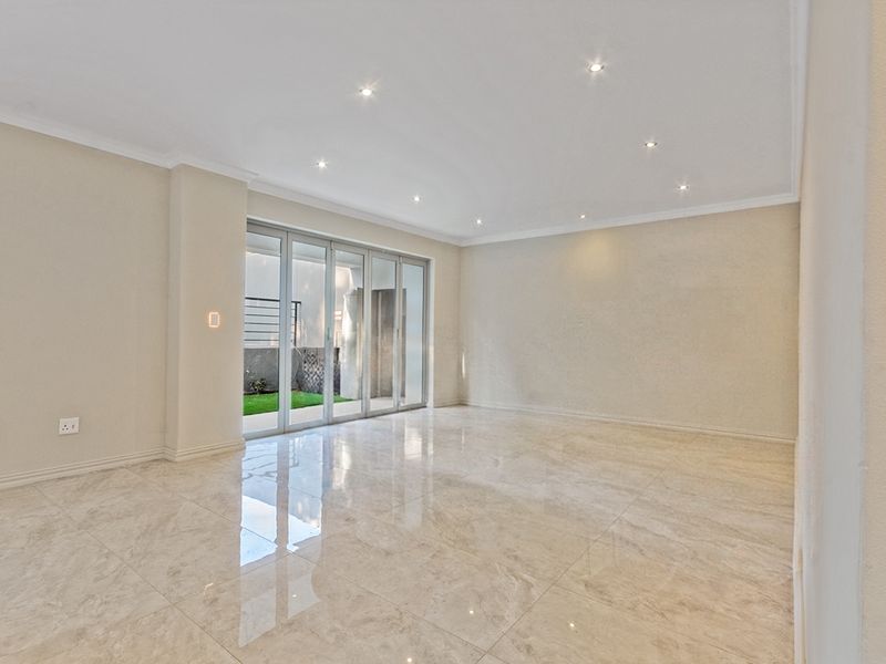 Spacious, empty living area featuring polished porcelain tile flooring, recessed downlighting, and large aluminium stacker doors providing access to the outdoor space.