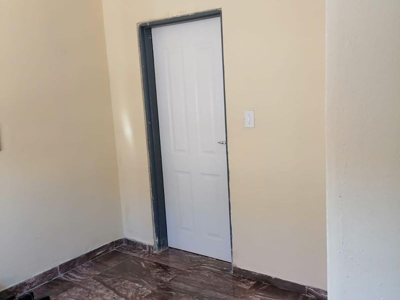 An empty bedroom featuring tiled flooring, cove cornicing, and an unfinished door frame, offering a blank canvas for renovation.