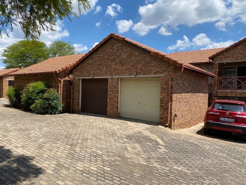 Exterior view of a residential property featuring a double garage with roller doors and a paved driveway.