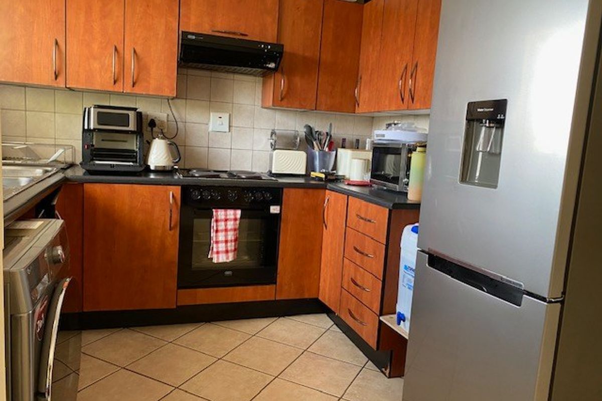 A functional kitchen featuring wood-finish cabinetry, tiled backsplash, and built-in cooking appliances, offering a practical layout for daily meal preparation.