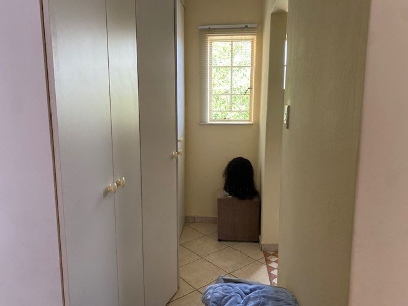 A functional hallway featuring built-in cupboards for storage, tiled flooring, and a window providing natural light.