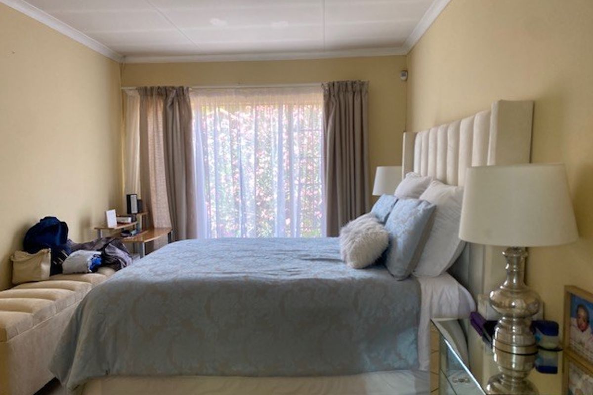 A well-lit bedroom featuring tiled flooring and classic ceiling cornicing, offering a comfortable and functional space.