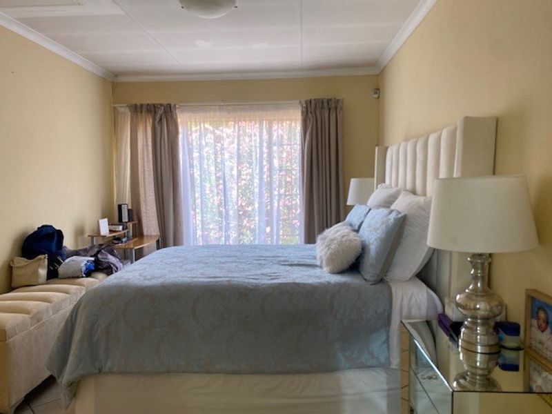 A well-lit bedroom featuring tiled flooring and classic ceiling cornicing, offering a comfortable and functional space.