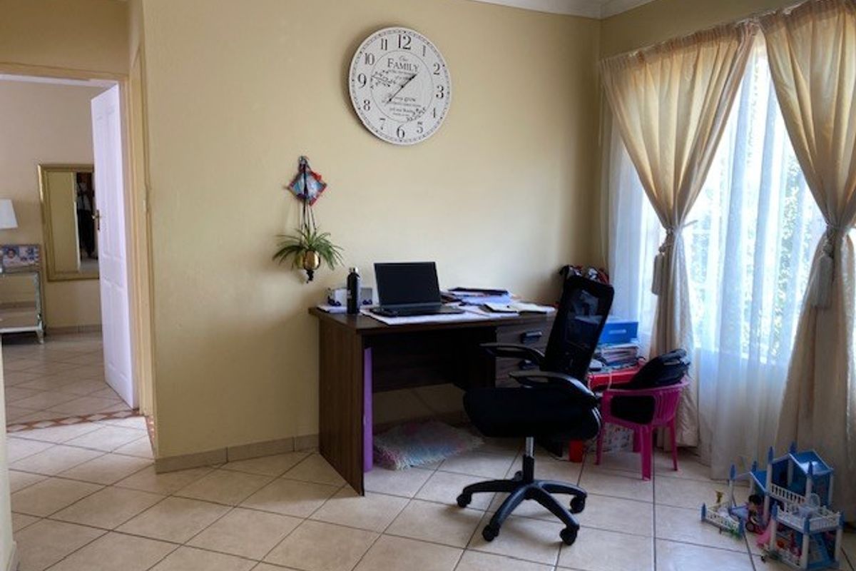 A living area featuring neutral wall paint, tiled flooring, and coved ceiling cornices, currently utilized as a home office space.