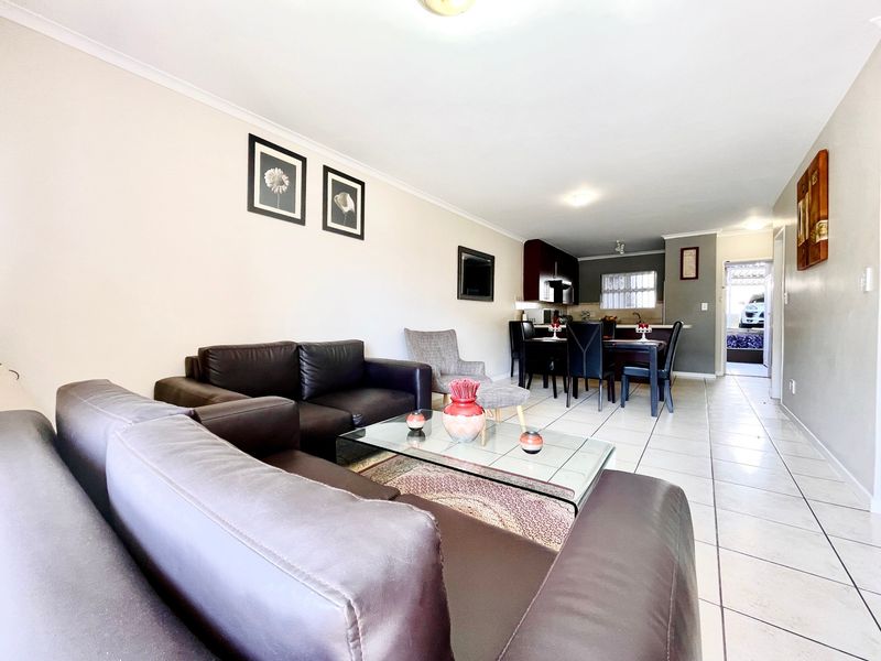 Open-plan living and dining area featuring tiled flooring and a functional kitchen space with built-in cabinetry.
