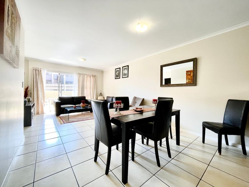 Spacious open-plan living and dining area featuring neutral tiled flooring and a sliding glass door providing access to the outdoor space.