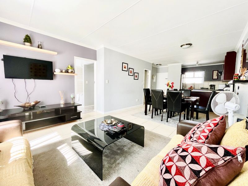 Spacious open-plan living and dining area featuring tiled floors and a connected kitchen space with built-in cabinetry.