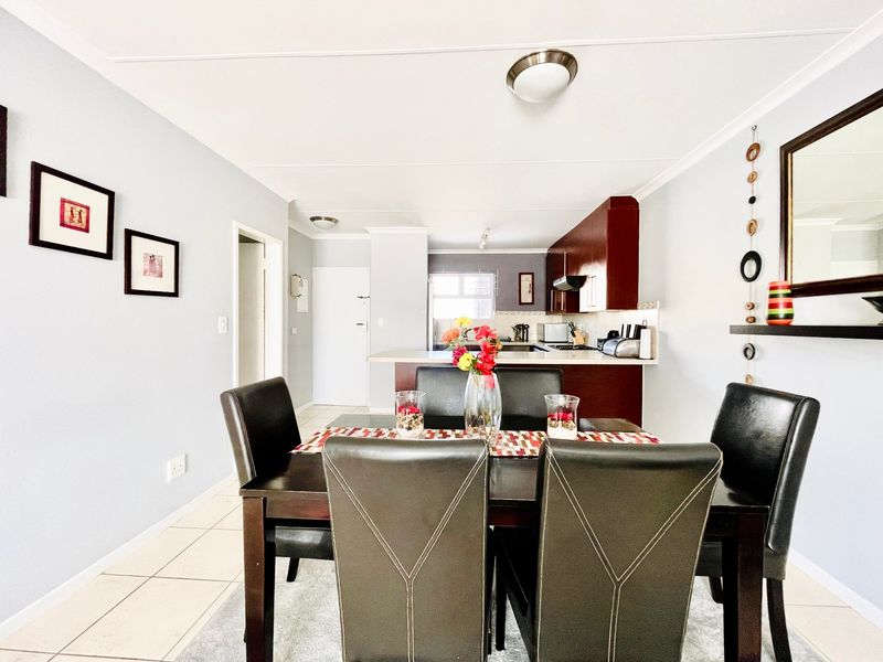 Open-plan dining and kitchen area featuring tiled flooring, dark wood cabinetry, and a breakfast bar, creating a functional living space.