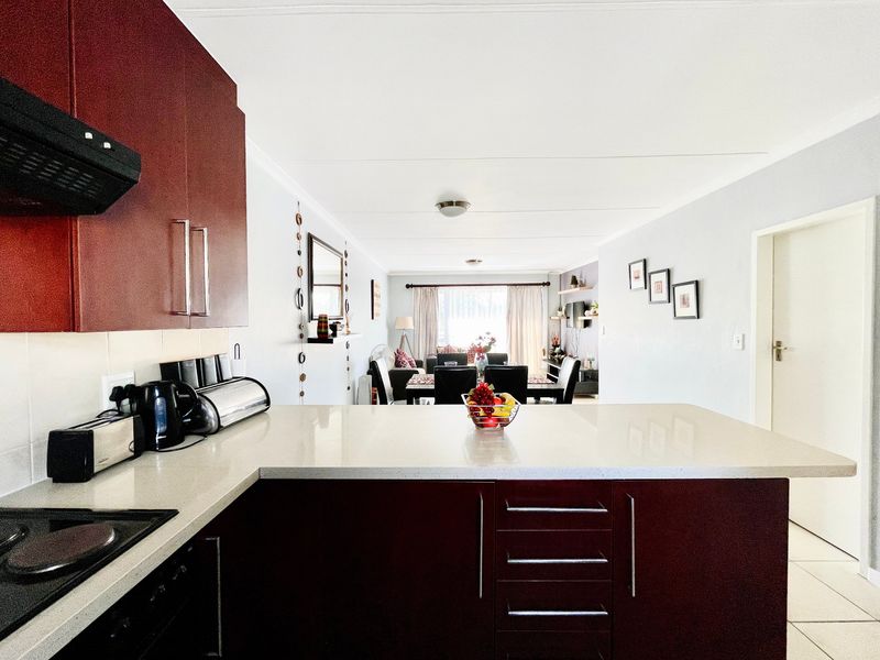 Open-plan kitchen and living area featuring dark cabinetry, stone countertops, and tiled flooring, creating a functional and connected living space.