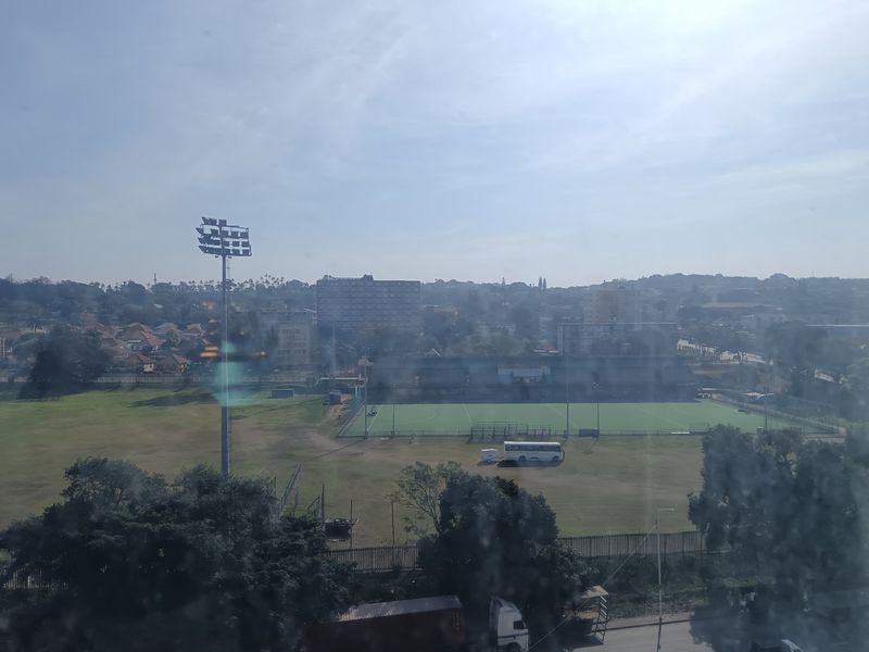 An elevated view overlooking a sports field and surrounding urban landscape.