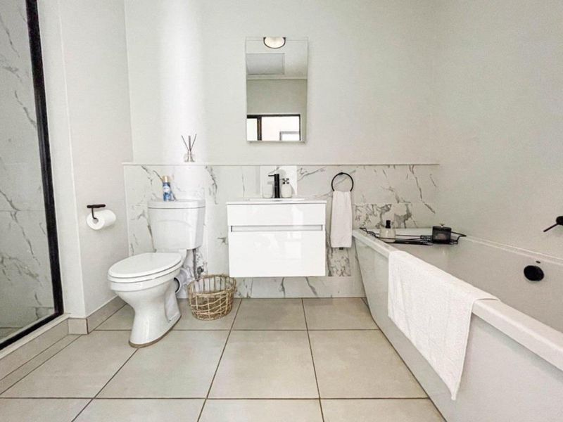 Modern bathroom featuring a wall-mounted vanity, marble-look wall tiling, a freestanding bathtub, and a separate glass-enclosed shower.