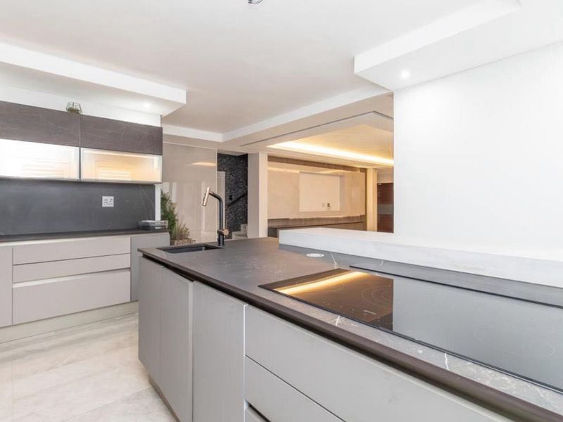 Modern kitchen featuring a sleek island with integrated hob, stone countertops, and contemporary cabinetry in a neutral palette.