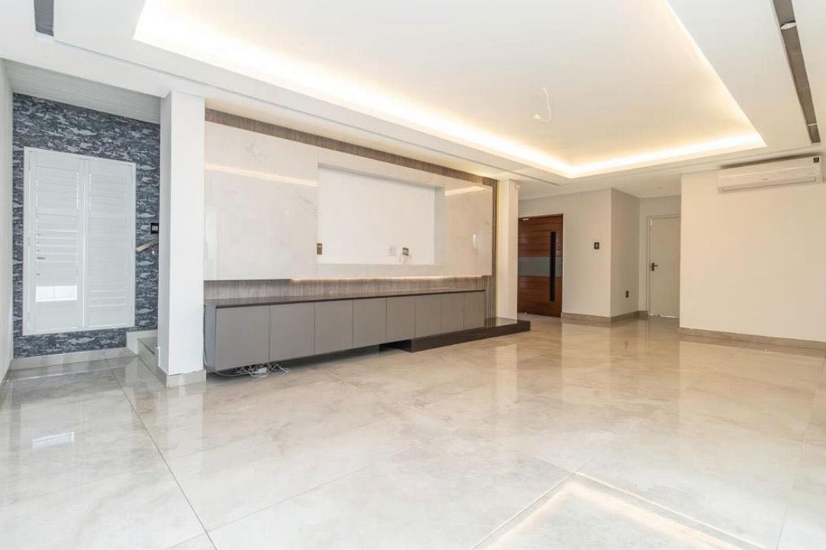 Spacious, modern living area featuring polished marble-look floor tiles, recessed ceiling lighting, and a sleek built-in media console with integrated cabinetry.