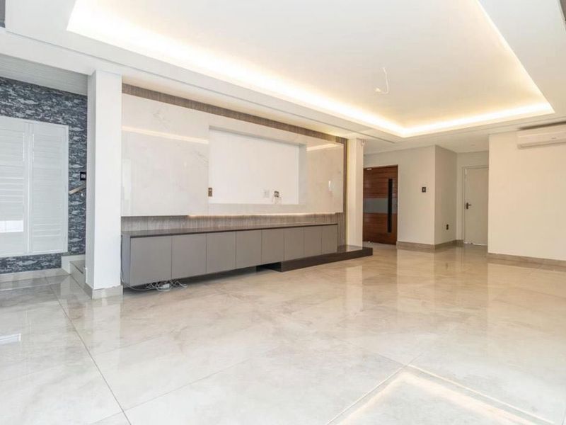Spacious, modern living area featuring polished marble-look floor tiles, recessed ceiling lighting, and a sleek built-in media console with integrated cabinetry.