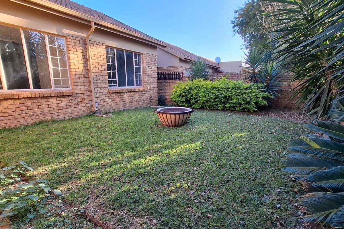 A private rear garden featuring a well-maintained lawn, face brick exterior walls, and established perimeter boundary walls.