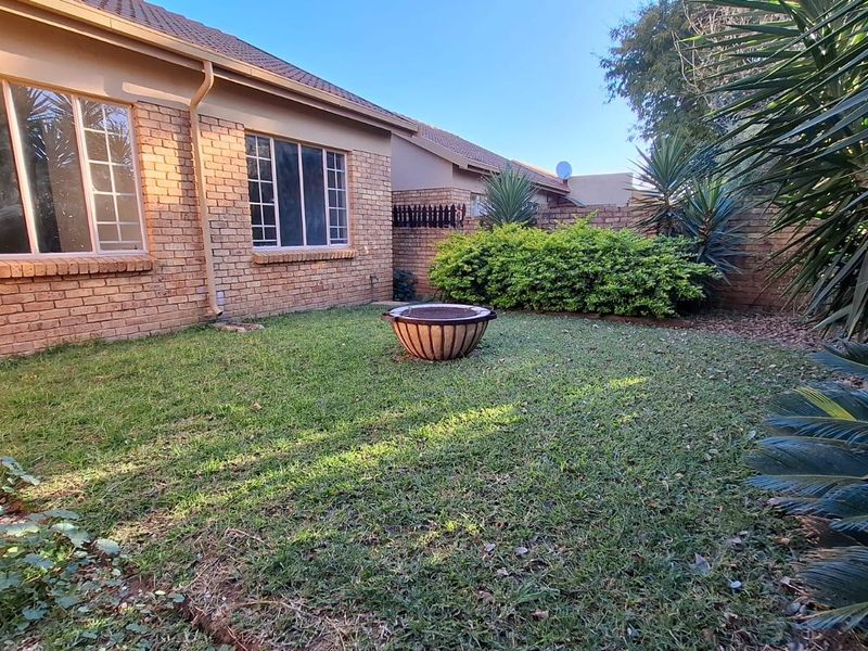 A private rear garden featuring a well-maintained lawn, face brick exterior walls, and established perimeter boundary walls.