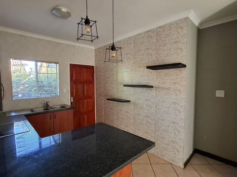 A functional kitchen featuring granite countertops, built-in cabinetry, a double basin sink, and tiled flooring, offering a clean space ready for modern updates.