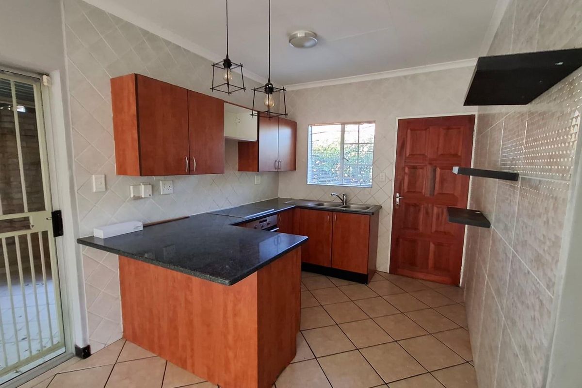 A functional kitchen featuring laminate cabinetry, granite countertops, tiled backsplash, and ceramic flooring, offering a practical layout with direct access to the exterior.