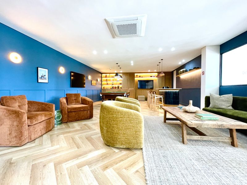 A modern open-plan living and entertainment area featuring herringbone timber flooring, a built-in bar, and sophisticated recessed lighting.