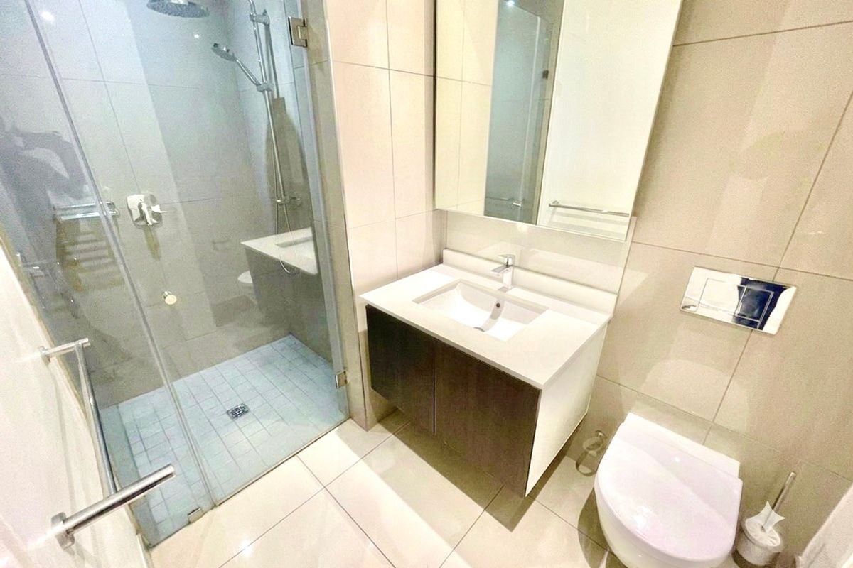 Modern bathroom featuring a walk-in shower with glass screen, wall-mounted vanity with integrated basin, and a wall-hung toilet with concealed cistern.