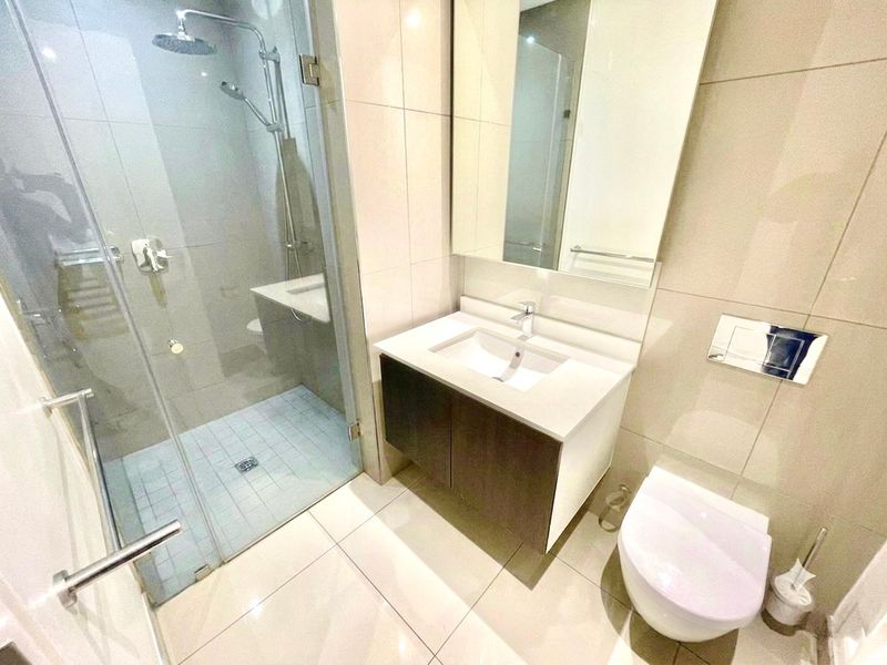 Modern bathroom featuring a walk-in shower with glass screen, wall-mounted vanity with integrated basin, and a wall-hung toilet with concealed cistern.