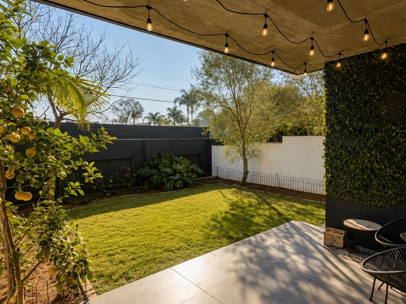 A covered patio area featuring tiled flooring, a concrete ceiling with string lighting, and a vertical garden wall overlooking a private lawn and garden.