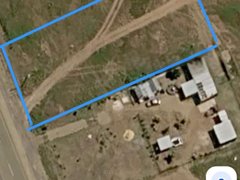 Aerial view of a vacant residential plot with a dirt access track, highlighting the property boundaries and surrounding landscape.