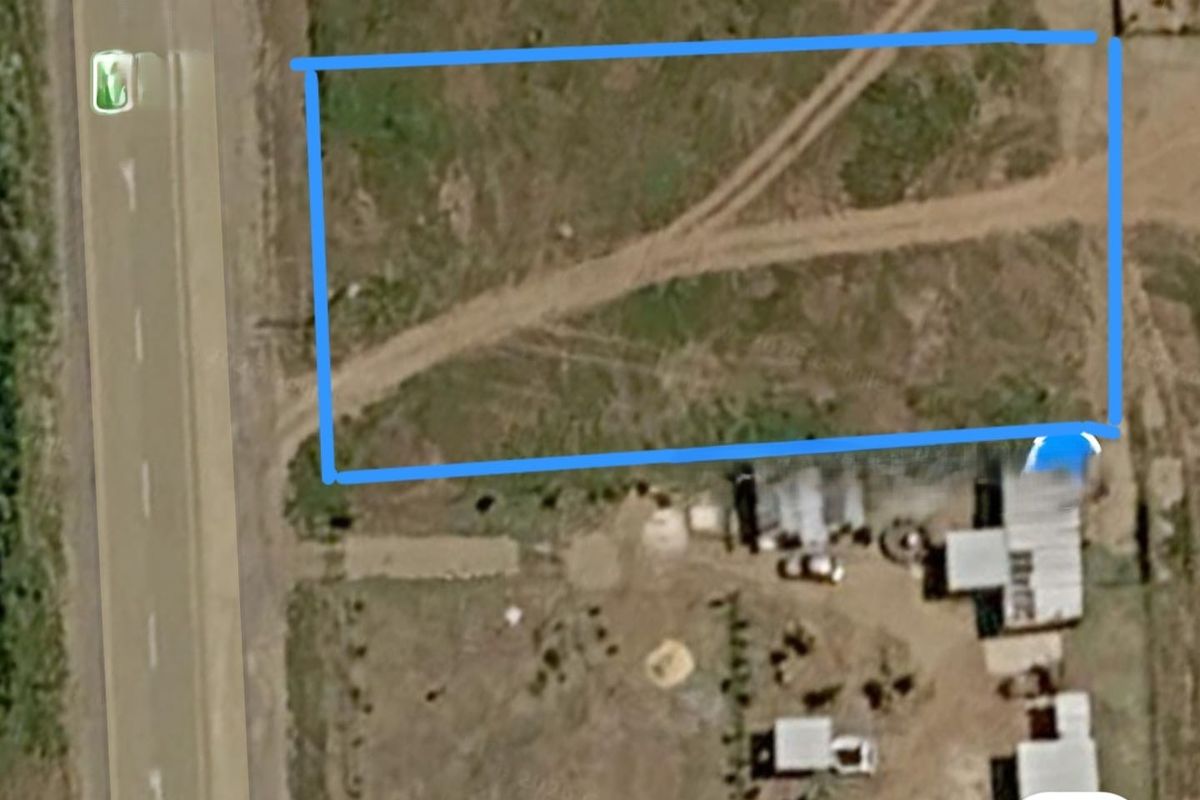 Aerial view of a vacant residential plot featuring natural terrain and direct access to the adjacent road.