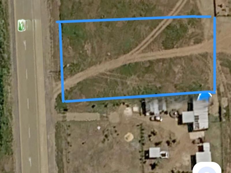 Aerial view of a vacant residential plot featuring natural terrain and direct access to the adjacent road.