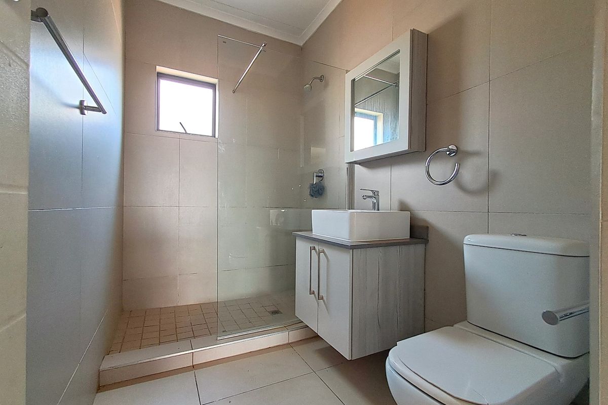 Modern bathroom featuring a walk-in shower with glass screen, vanity cabinet with vessel sink, and a wall-mounted mirror cabinet.