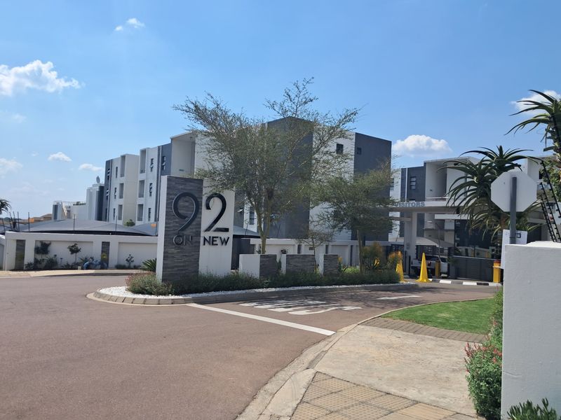 Front entrance view of the 92 on New apartment complex, featuring modern signage, secure access gate, and well-maintained paved driveway and landscaping.