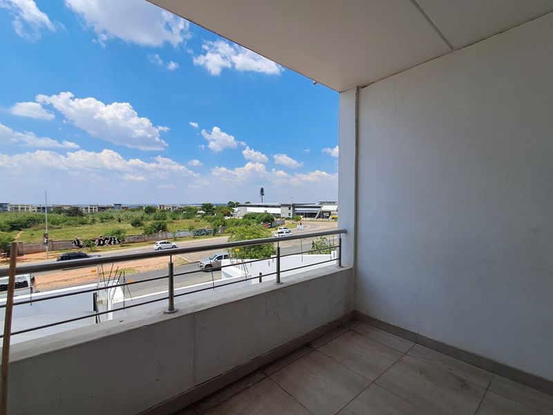 A private balcony featuring tiled flooring and a stainless steel balustrade, offering an elevated view of the surrounding area.