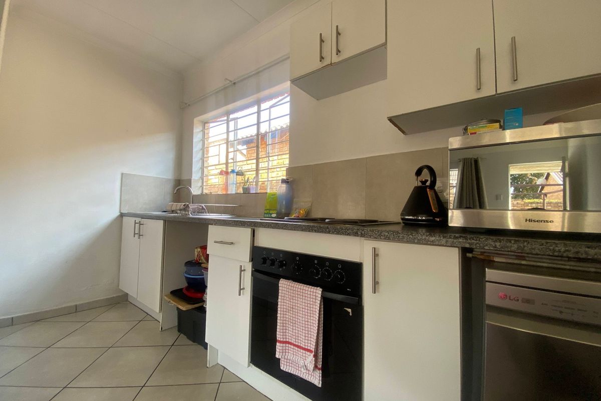 Functional kitchen featuring white cabinetry, granite countertops, built-in oven, hob, and tiled flooring. Includes a dedicated space for a dishwasher.