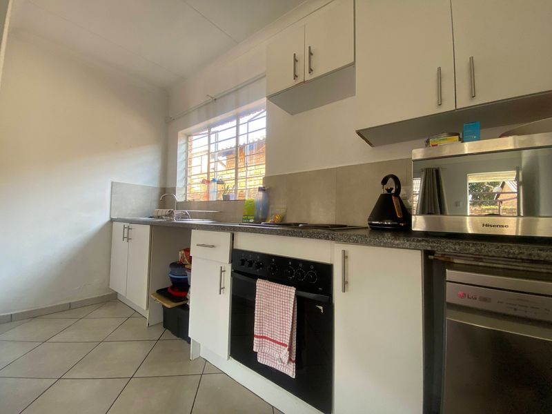 Functional kitchen featuring white cabinetry, granite countertops, built-in oven, hob, and tiled flooring. Includes a dedicated space for a dishwasher.