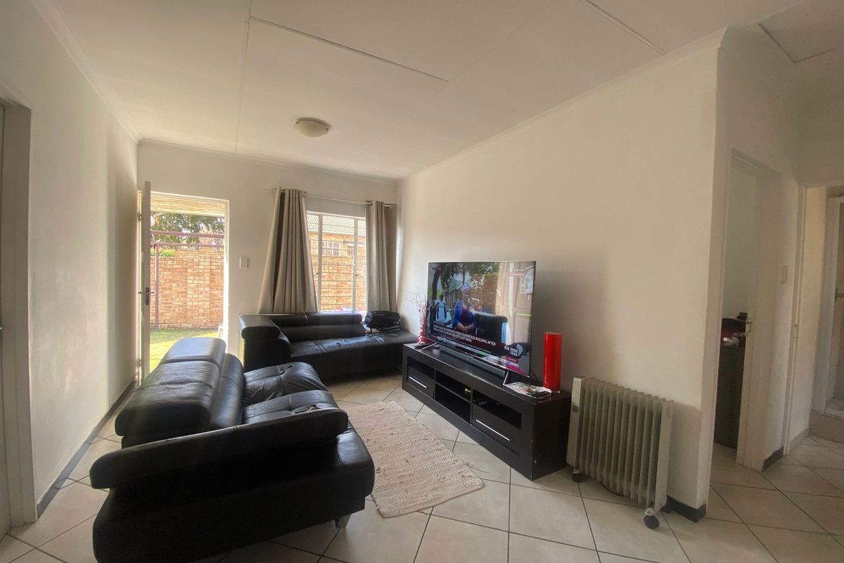 A living room featuring tiled flooring and direct access to an outdoor area, providing a functional space with neutral finishes.