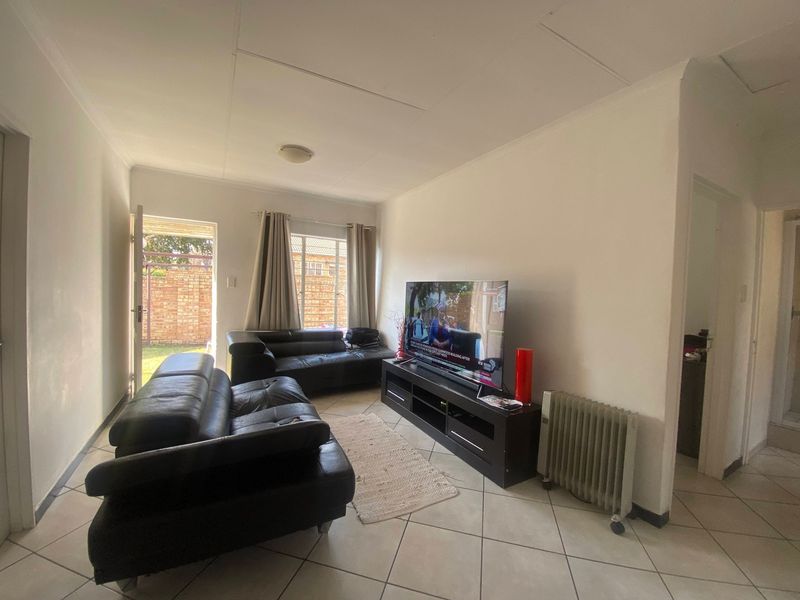 A living room featuring tiled flooring and direct access to an outdoor area, providing a functional space with neutral finishes.