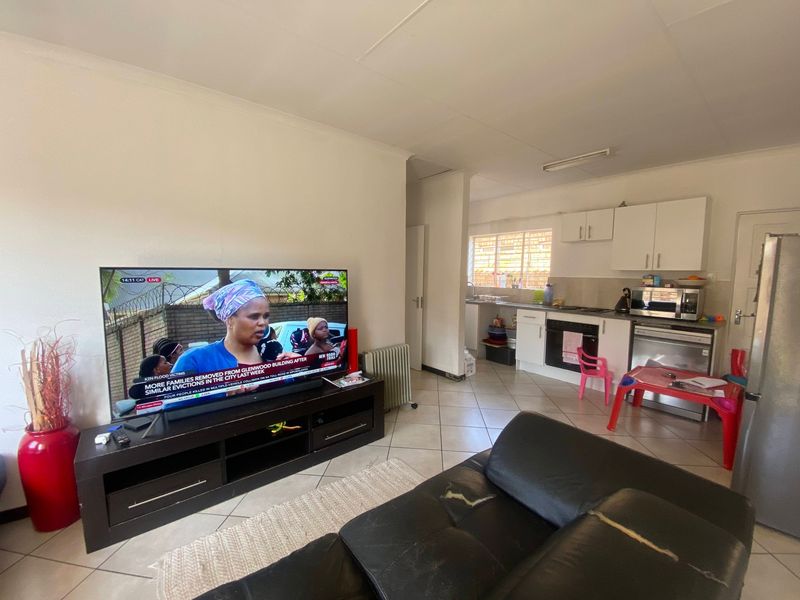 Open plan living area featuring tiled flooring and a functional kitchen with built-in cabinetry, oven, and hob.