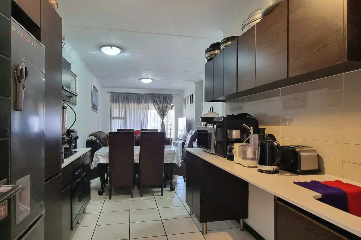 Open plan kitchen and dining area featuring dark wood cabinetry, tiled flooring, and a functional layout suitable for modern living.