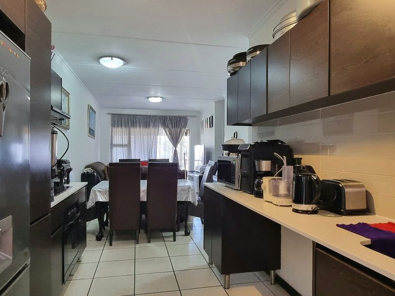 Open plan kitchen and dining area featuring dark wood cabinetry, tiled flooring, and a functional layout suitable for modern living.