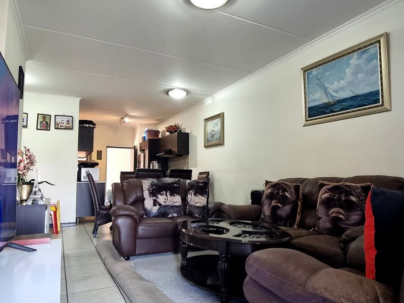 Open-plan living and dining area featuring tiled flooring and integrated kitchen space, providing a functional layout for daily living.