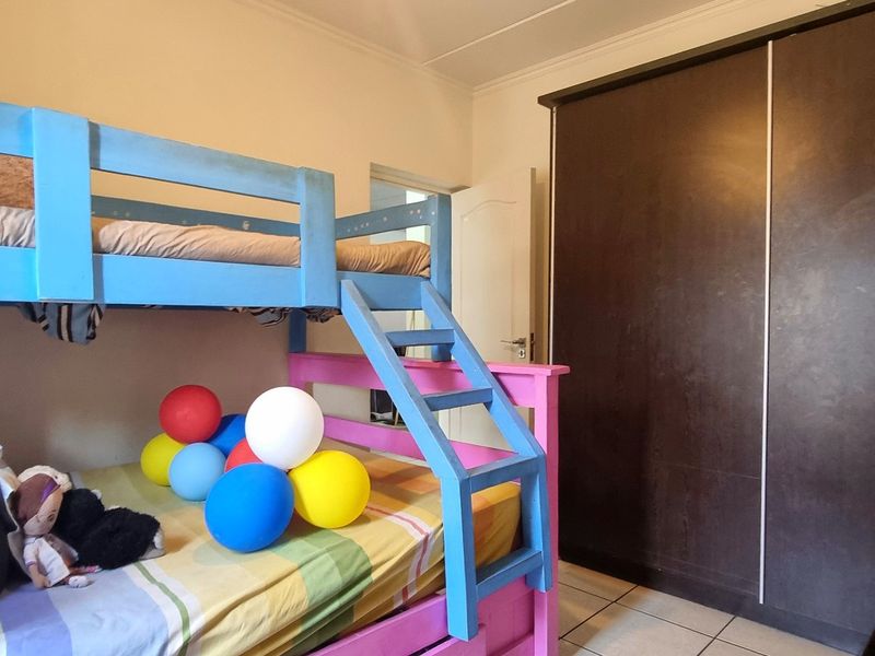A bedroom featuring tiled flooring and a large dark-toned built-in wardrobe with sliding doors.