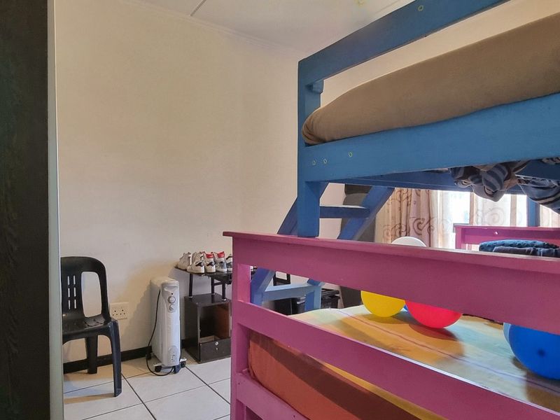 A bedroom featuring tiled flooring and a built-in cupboard, currently utilized as a children's room.