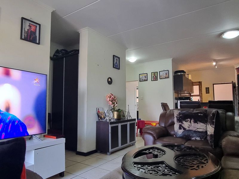 An open-plan living area featuring tiled flooring and integrated lighting, connecting the lounge space to the kitchen area.