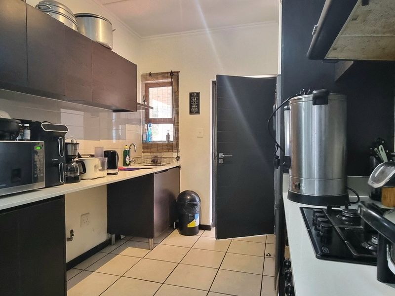 A functional kitchen featuring dark cabinetry, light countertops, tiled backsplash, and a gas hob with an integrated extractor fan.
