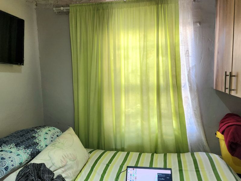 A compact bedroom featuring built-in cabinetry and decorative ceiling molding, currently showing signs of wear and requiring cosmetic updates to the walls and ceiling.