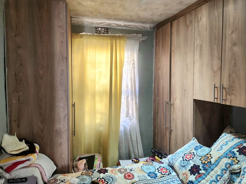 A bedroom featuring extensive built-in wooden cabinetry and a window with curtains, providing ample storage space.