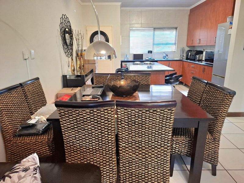 Open-plan kitchen and dining area featuring wood-finish cabinetry, a central kitchen island, and tiled flooring throughout.