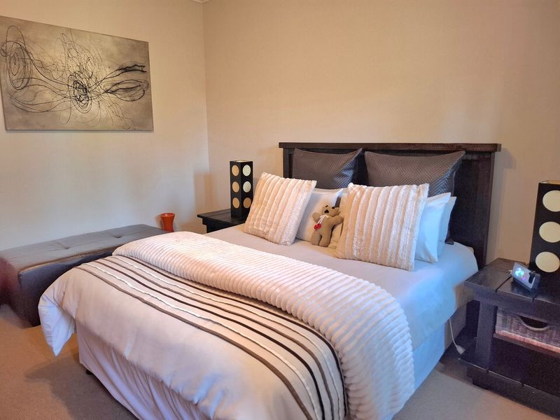 A well-maintained bedroom featuring neutral wall tones and carpeted flooring, providing a comfortable and inviting space.